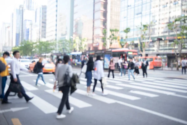 Abstract blurred of busy city people crowd walking on zebra crossing street with modern building as background, korea, asia