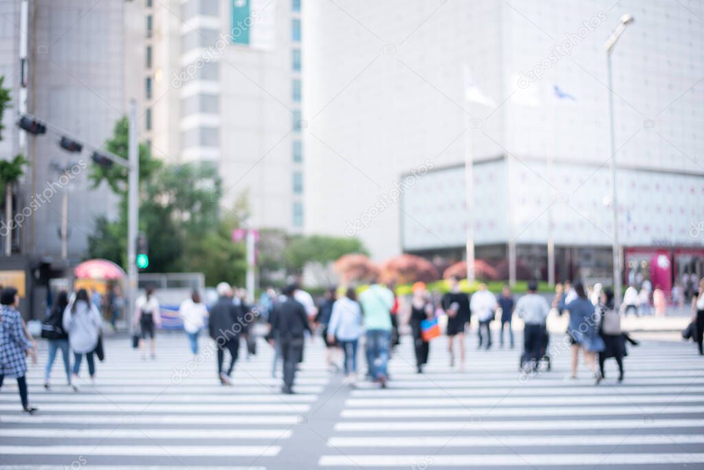 Abstract blurred of busy city people crowd walking on zebra crossing street with modern building as background, korea, asia