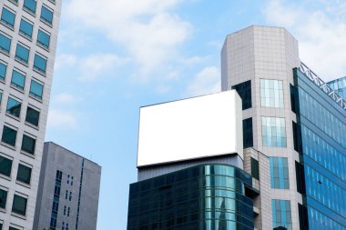 Blank advertising billboard on top of modern building in the city with blue sky background useful for products advertisement