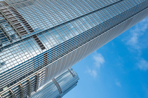 Low angle view of skyscraper with architecture and glass window exterior of building around business area in Hong Kong and blue sky