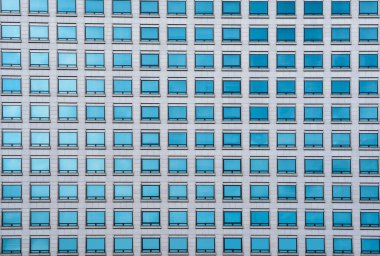 Şehirde gökyüzü ve bulut yansıması olan modern ofis binalarının yeşil cam pencereleri.