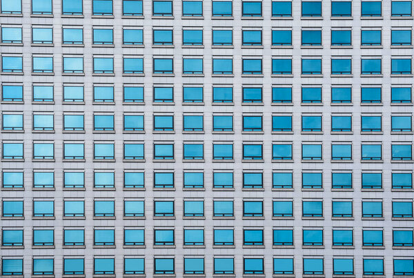 Pattern of green glass windows of modern office buildings in the city with sky and cloud reflection
