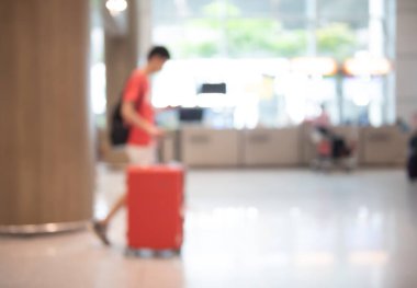Blurred asian young man, traveler, tourist with baggage walking in airport corridor, holiday weekend travel for background, side view, motion blur