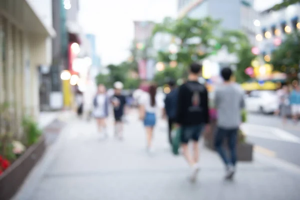 Blurred young people walking on pedestrian at outdoor shopping center in the city with colorful bokeh, Seoul, Korea