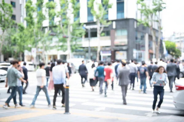 Blurred background of crowd anonymous people walking  on pedestrian and  waiting for traffic light and crossing the street on zebra crossing in the city, business center, Seoul, Korea