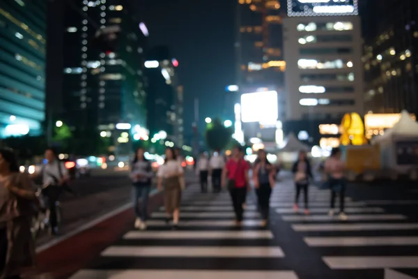 Blurred people crossing the street in the city at night with cars, traffics light and buildings as background, Night life in Korea