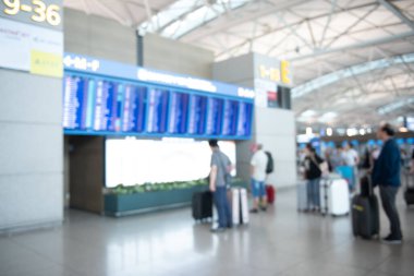 Blurred of  passengers, travelers with baggage checking fligt form  flight information board at airport terminal for background