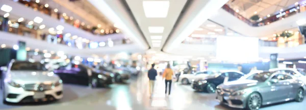 Blurred background of new cars displayed in luxury showroom with light bokeh, motor show event, panorama