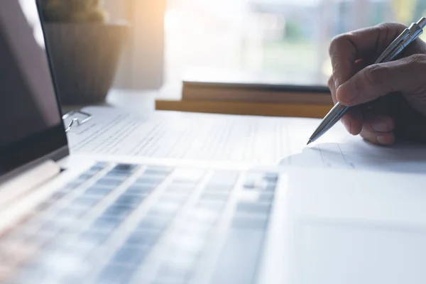 Businessman signing official contract with laptop computer on office desk. business agreement, deal concept. close up