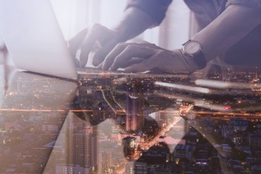 Gece dizüstü bilgisayarda ve şehir manzarasında çalışan çifte teşhirci iş adamı, modern teknoloji, akıllı iş, internet düşünceleri konsepti.
