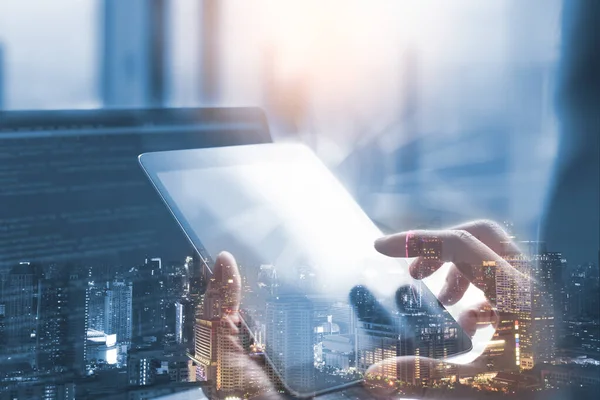 IoT, internet of Things concept. Business man or software engineer  working on digital tablet with wireless network globalization interface,  coding program on laptop computer double exposure with smart city