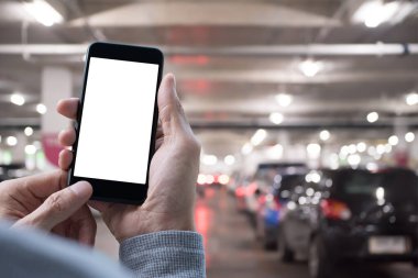 Mockup image, man hands holding blank screen mobile smart phone in indoor car parking. Mobile app concept
