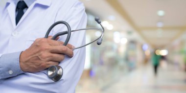 Erkek doktorun steteskopla el ele tutuşup hastane içi geçmiş, sağlık sigortası konsepti....