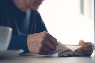 Closeup image of young asian man reading a book. Casual man, student opening and relaxed reading book in university library, vintage style.