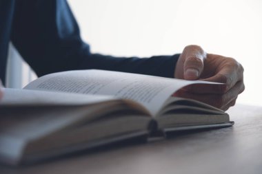 Closeup image of young asian man reading a book. Casual man, student opening and relaxed reading book in university library, vintage style.