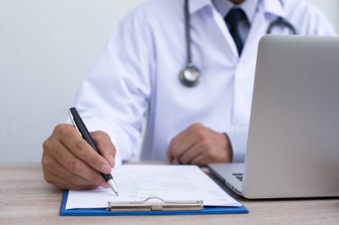 Dizüstü bilgisayarda çalışan ve sağlık kontrol listesi ya da hastanın geçmişini dolduran erkek doktor, kapatın. Teletıp, EMRs Electronics Medical Records sistemi, EHRs Electronic Health Records sistem konsepti