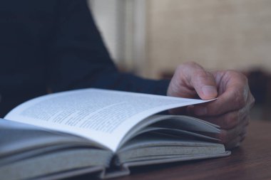 Genç Asyalı bir adamın kitap okurkenki görüntüsü. Sıradan bir adam, öğrenci açılışı ve gevşetilmiş kitap üniversite kütüphanesinde ahşap masanın üzerinde, klasik tarzda..