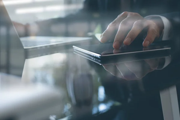 Professional business man in black suit working on laptop computer and using digital touch screen tablet in modern office,  business and technology concept