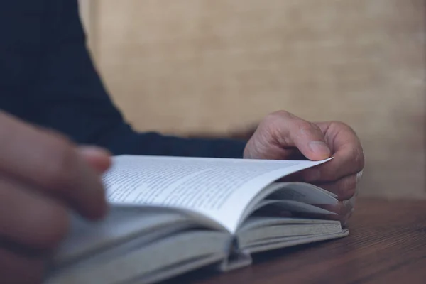 Closeup image of young asian man reading a book. Casual man, student opening and relaxed reading book on wooden table in university library, vintage style.