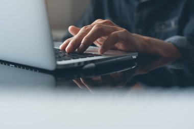 Casual business man, hipster hand typing on keyboard, working on laptop computer on desk in modern office or home office, online working concept, close up