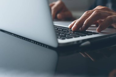 Casual business man, hipster hand typing on keyboard, working on laptop computer on desk in modern office or home office, online working concept, close up