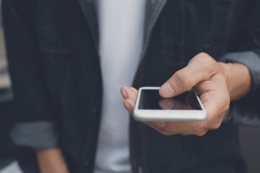 Casual man, hipster in black shirt using mobile smart phone checking internet application, touching smartphone screen with reflection, close up, toned image