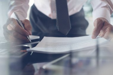 Work process concept. Businessman using calculator to calculate accountancy document with laptop computer on desk. Corporate man hand holding a pen working in modern office, close up