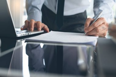 Signing contract, business deal concept. Business man standing and make a deal, signing official document with laptop computer on desk in modern office, close up