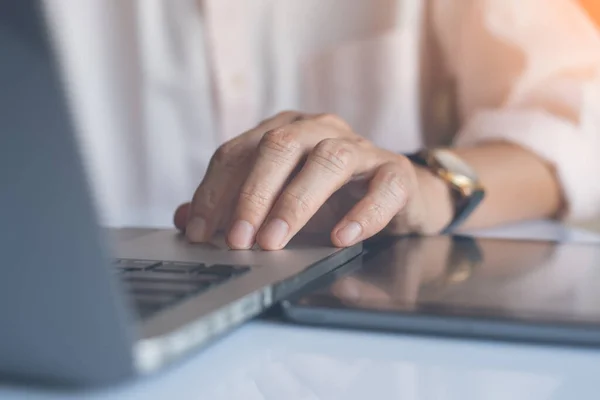 Close up of businessman working on laptop computer and tablet pc and rest his hand on keyboard with reflection, online working internet of things IOT.