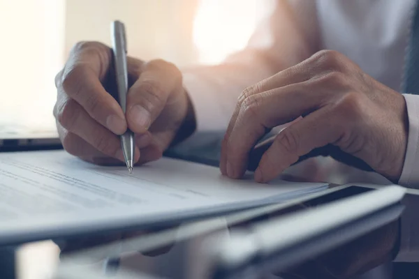 Signing contract, business agreement, deal concept. Business man signing official contract with a pen on desk in modern office with morning sunlight, close up