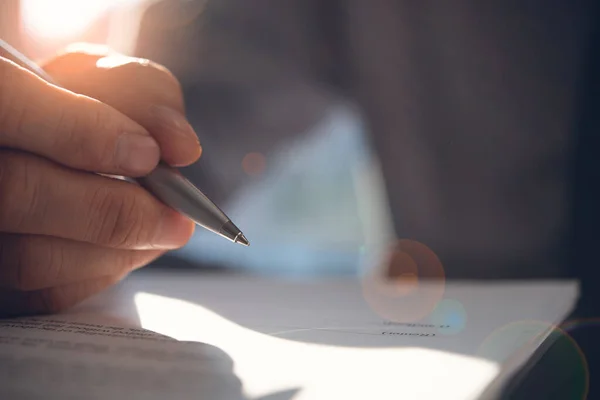 Business agreement, deal concept. Businessman reading rental contract before making a deal. Corporate man with pen in hand working in modern office, signing business document on desk. close up. Flare light effect