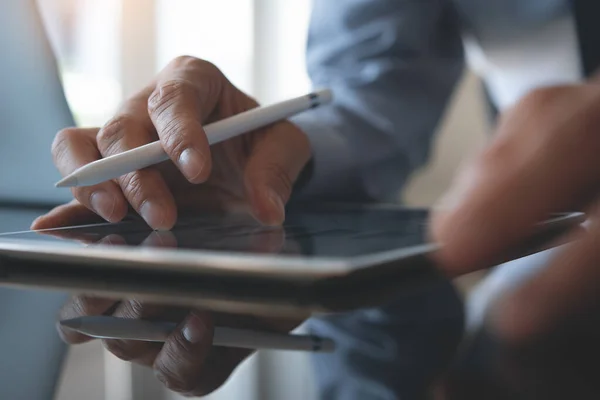 Businessman or corporate man zooming in digital tablet computer analyzing business report with digital diagram, financial graph while working on laptop computer in office, business analysis concept