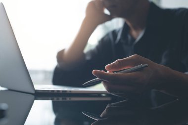 Young Asian business man feeling stressed and frustrated while working on laptop computer. Male entrepreneur getting in trouble with his job. Freelance lifestyle at modern office, dark tone