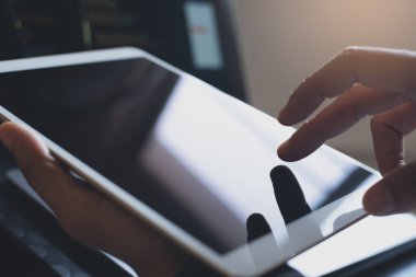 Digital software technology development, web or application design concept. Man programmer, software developer hand touching on digital tablet while working on laptop computer in office, close up