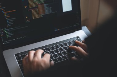 Web or application development, business and technology concept. Programmer, man software developer hands coding HTML, programming Javascript on laptop computer screen, back view close up
