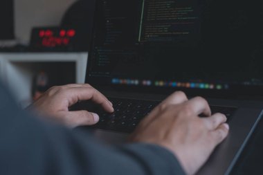 Web or application development, business and technology concept. Programmer, man software developer hands coding HTML, programming Javascript on laptop computer screen, back view close up