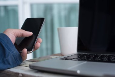 Young casual man, freelance working from home drinking coffee and laptop computer connecting internet, freelance lifestyle, online working concept, close up