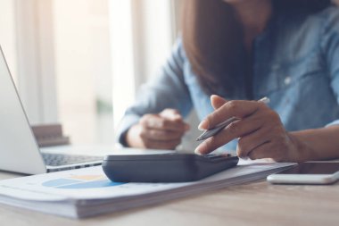 Smart business woman using a calculator to calculate business profit, review paper report, business atrategy analysis, cropped image