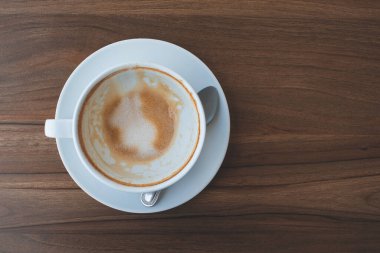 Empty cup of latte or cappuccino coffee with frothy foam on wooden table and copy space, top view
