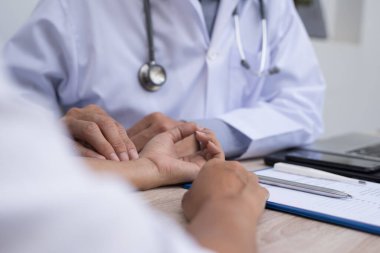 Doctor taking patient's pulse at outpatient department in hospital. Doctor taking physical examination of female patient in clinic, close up