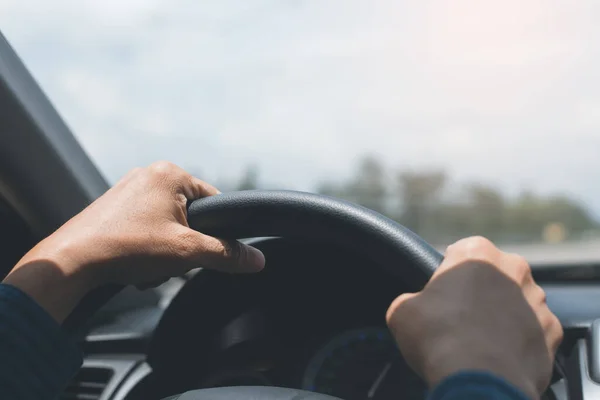 Man holding streering wheel, driving a car in sunny day, close up