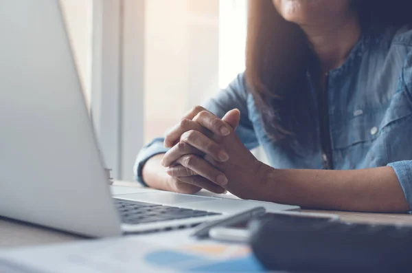 Casual business woman or freelancer working on laptop computer and smartphone on office desk, crosses his hands with stress, waiting for internet loading, thinking about work, start up business