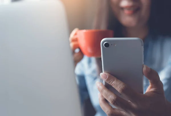 Video calling, business  woman smiling and talking via smart phone video camera  application at home,  working on laptop computer on coffee break time