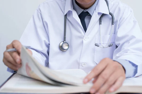 Cropped image, male doctor reading anatomy textbook. Medical sudent reading book in medical school, education concept, close up.