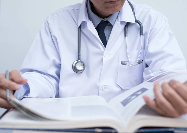 Cropped image, male doctor reading anatomy textbook. Medical sudent reading book in medical school, education concept, close up.