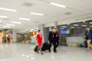 Abstract background,  blurred  image of  stewards and stewradesses  with suitcases walking in passenger terminal at the airport.