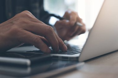 Sıradan bir iş adamı, dizüstü bilgisayar klavyesinde daktilo yazan bir serbest yazar. Kalem tutan adam, akıllı telefonlu internet taraması, masadaki dijital tablet, ev ofisinden online çalışma, klasik ton.