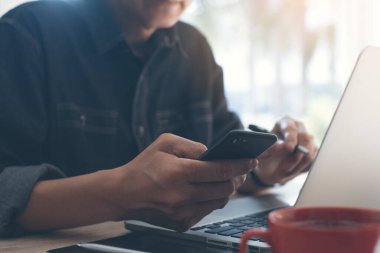 Sıradan bir iş adamı, cep telefonu kullanan serbest çalışan, dizüstü bilgisayarla çalışan. İnternette bir fincan kahve, masada dijital tablet ev ofisinden online çalışma, serbest çalışma konsepti