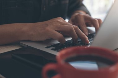 Sıradan bir iş adamı, dizüstü bilgisayar klavyesinde daktilo yazan bir serbest yazar. Adam internete bir fincan kahve, akıllı telefon, masasında dijital tablet, kafeden internet üzerinden bakıyor..