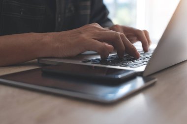 Sıradan bir iş adamı, dizüstü bilgisayar klavyesinde daktilo yazan bir serbest yazar. Adam interneti akıllı telefonla geziyor, dijital tablet ahşap masada, internet üzerinden çalışıyor, kapat..